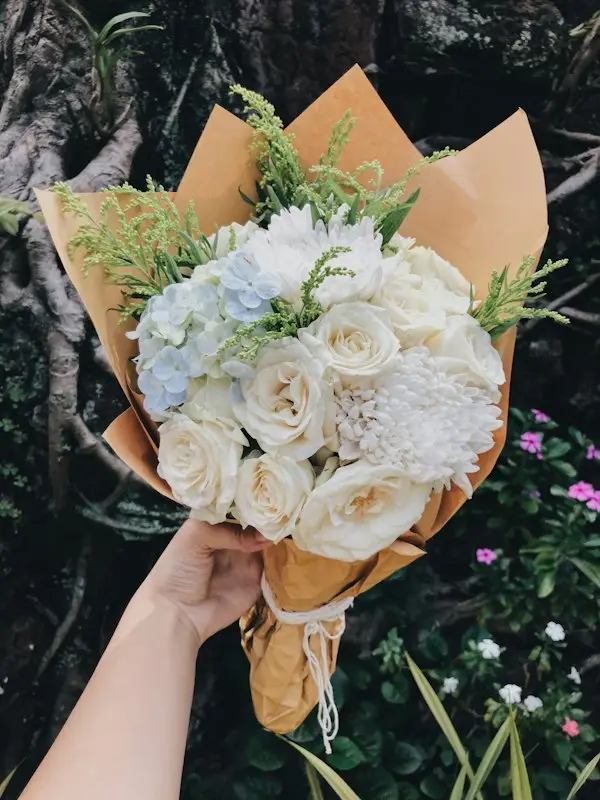 A person holding a wrapped bouquet for delivery